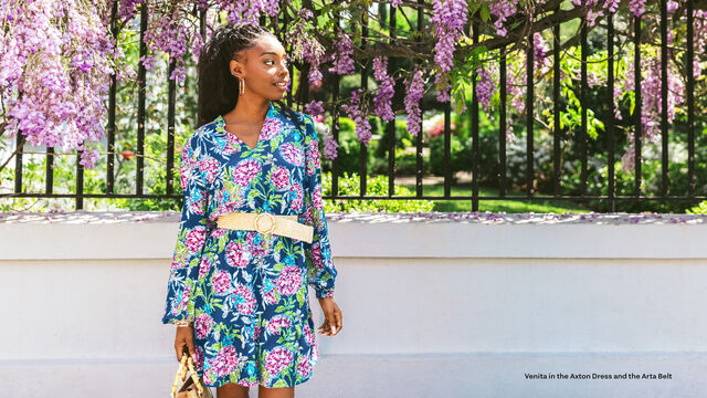 Venita Aspen wearing colorful floral printed dress in front of gate in Charleston